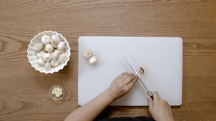 Chef cuts mushrooms on the cutting board, top view