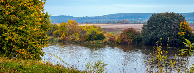 Autumn landscape. Colorful trees by the river in autumn on a sunny day