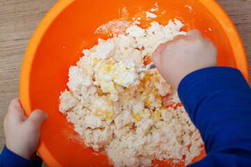 child prepare delicious cheesecakes from cottage cheese dough in the bowl