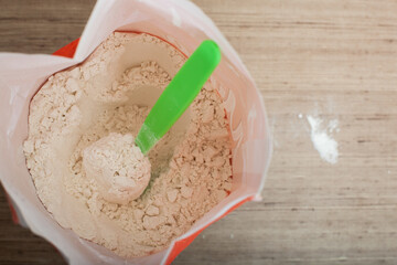 Opened package with flour and spoon inside on the kitchen table for cooking various dishes