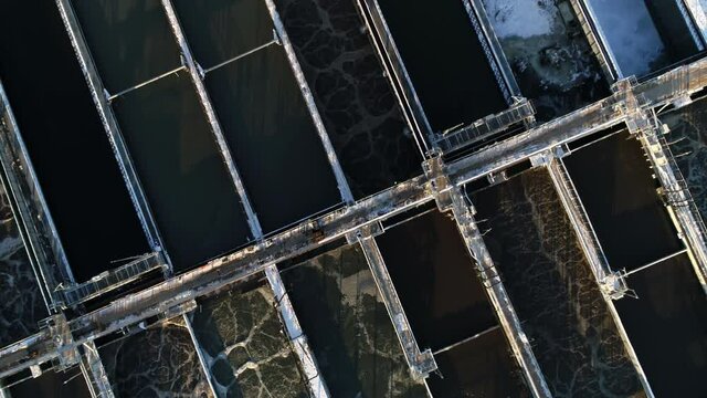 Set of reservoirs with processing waste water at contemporary filtration station on snowy land in winter evening aerial view