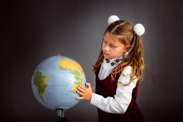 Girl child schoolgirl in school uniform with globe, classic school photos, dark background