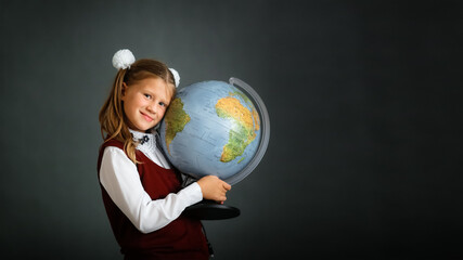 Girl child schoolgirl in school uniform with globe, classic school photos, dark background