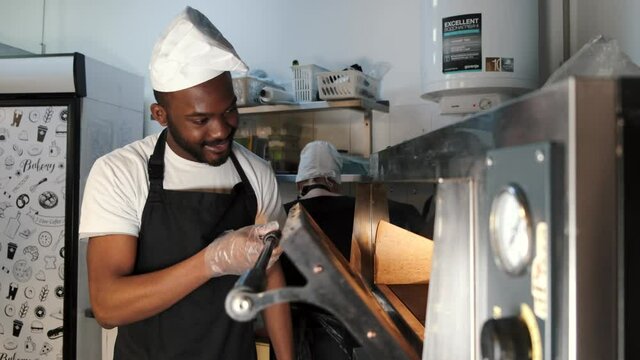 African merican man baking pizza at commercial kitchen