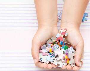 The child holds the details of a colored puzzle. Pieces of the puzzle in the hands of a child.