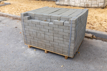 New paving slabs packed in stack on wooden pallet before laying. Building materials at construction site