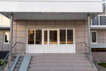 Entrance lobby with a metal canopy, ramp and plastic doors in an apartment building. Social housing
