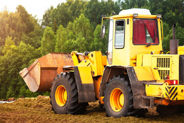 Obraz na płótnie Canvas A yellow bulldozer is compacting a green mass of cut grass. 