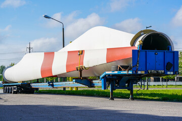 A view of a truck, a low-loader semi-trailer with oversized wind generator parts in the parking lot