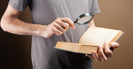 man reading a book using a magnifying glass