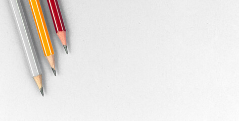 Obraz premium Background on the theme of education with colorful pencils on white silver office desk with copy space, top view photo