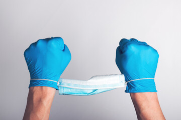 Medical gloves on hands and a face mask. The face mask binds the hands like handcuffs.