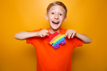 a cheerful child holds a fashionable anti-stress silicone toy in front of him and tries to stretch it