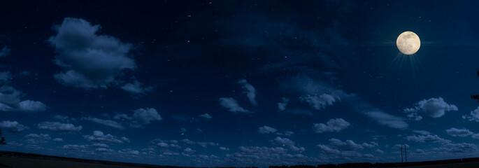 Panorama of night sky with clouds and stars. Moonlight.
