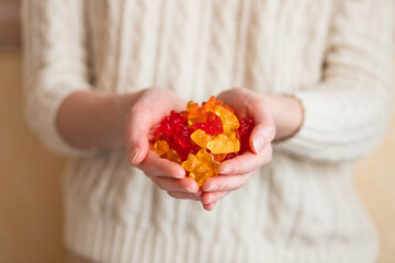Close-up image of a woman holding multi-colored gummy bears.