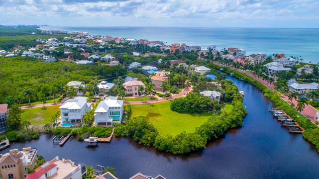 Aerial view of waterfront homes on the bay with the Gulf of Mexico in the background and luscious greenery all around