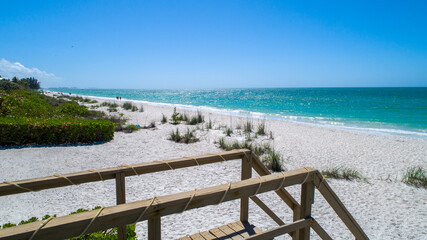 Fototapeta na wymiar Natural beach with wooden walkway going to the sand