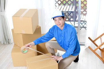 作業服を着た男性が引っ越しの段ボールを梱包するイメージ