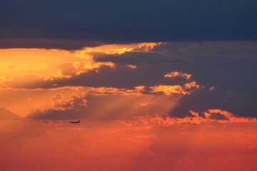 Beautiful sunset. Airplane in the sky against the background of the dark sky. High quality photo