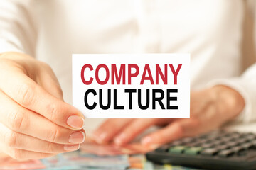 a woman in a white shirt holds a piece of paper with the text: company culture, business concept.