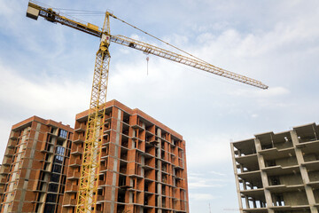 Fototapeta na wymiar High-rise residential apartment buildings and tower crane under development on construction site. Real estate development.