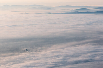 Surreal aerial view of Santa Maria degli Angeli church in Assisi, Italy, above a sea of fog