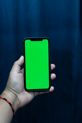 Man's hand shows mobile smartphone with green screen in vertical position isolated