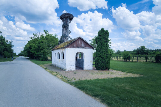 Small church on th field. Small chapel with old tree with nest of a stork on the top.