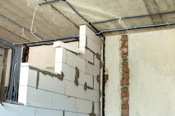 Electrical cables laid in protective corrugation installed on the ceiling and wall in a room under...