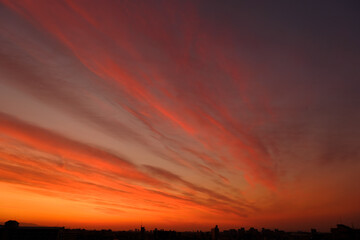 神戸市東灘区の高層マンションからの日の出、東の空がオレンジ色に染まり、神戸・芦屋・西宮の街並みがシルエットで浮かぶ。一日の始まり。