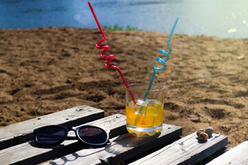 a glass of orange juice, sunglasses on the beach
