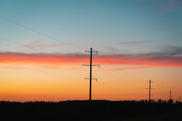 Poles with wires at sunset, in the evening.