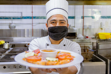 Portrait of Mexican Chef presenting plate in kitchen