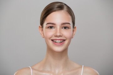 Portrait of a cute smiling girl in braces. Gray background.