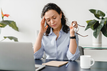 Depressed caucasian mature middle-aged businesswoman feeling headache on workplace, suffering from...