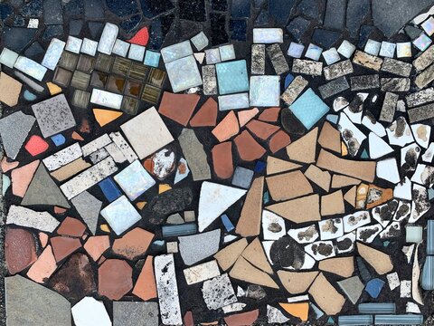 Colorful tile mosaic wall, mixed tiles and glasses on a concrete wall.