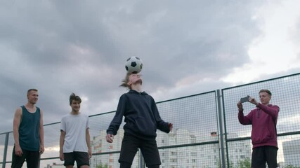 young happy smiling amateur football players perform tricks with the soccer ball before to start a friendly match or training workout game on court in a sunny day. 4K RAW graded footage