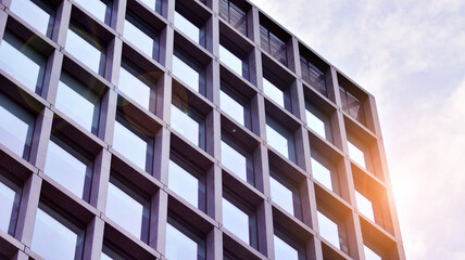 Obraz premium Abstract image of looking up at modern glass and concrete building. Architectural exterior detail of office building. Industrial art and detail. Sunrise.