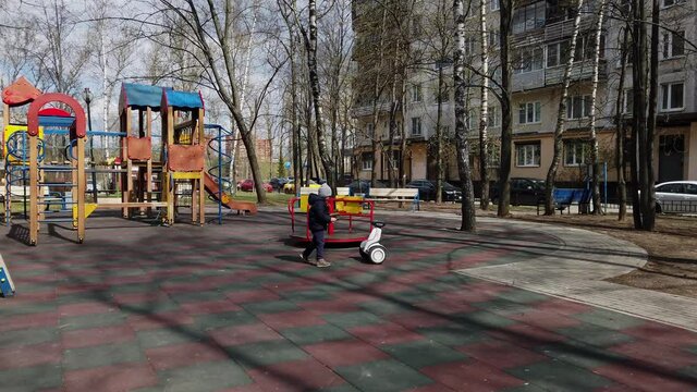 little boy funny playing on the playground with the help of new technology segway gadget in early spring