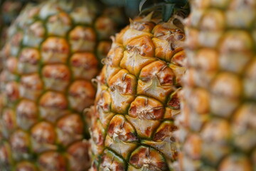 Fototapeta premium Pineapple in a row at market with selective focus on the pineapple in the middle.