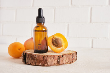 apricots and glass brown bottle with dropper for cosmetics on white brick wall background