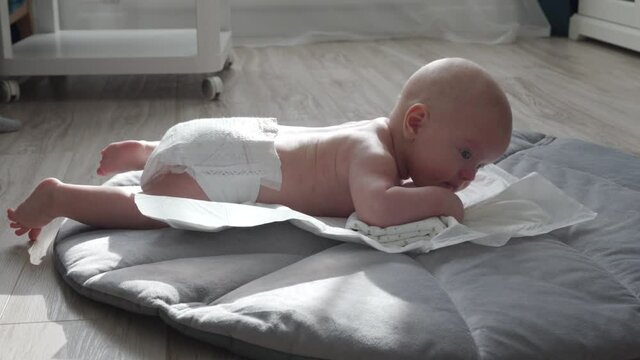 Tummy time for babies, baby learn head control, 3 month old baby boy lifting head lying on tummy on activity play mat at home. High quality 4k footage