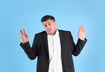 Man in suit avoiding something on light blue background