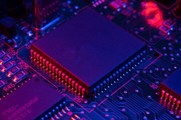 Electronic circuit board components chips resistors illuminated with neon light