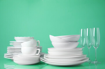 Set of clean tableware on light green background. Space for text