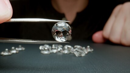 MACRO: Jeweler holding a diamond with tweezers showing it close-up.