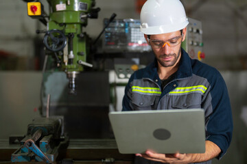 Mechanical engineer holding the laptop computer and working for maintenance or repairing the machine in factory.