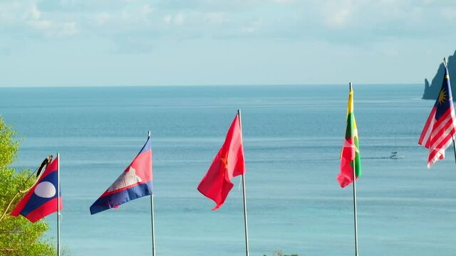 Blowing flags of ASEAN community - Laos, Cambodia, Malaysia, Vietnam, and union of Myanmar -Fluttering freely in sea background, mountains, and blue sky. And beautiful scenery of the island.