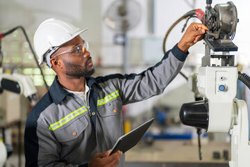 African mechanical engineer working for maintenance or repairing robotic welding machine in factory.