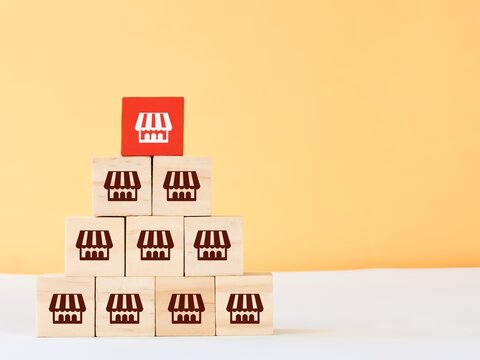 Pyramid shape wooden blocks with store icons. Franchise business system concept.